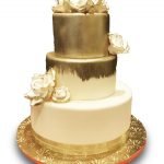 Fondant covered wedding cake brushed gold with gumpaste roses
