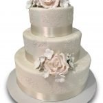 Three tiered fondant covered cake with ivory ribbon, edible lace and gumpaste flowers