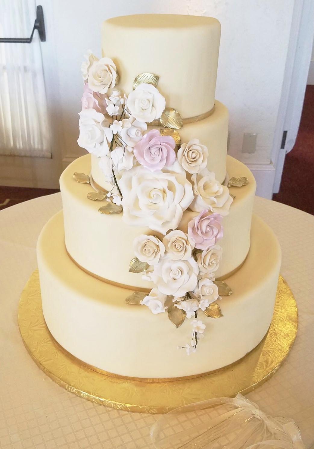 A3. White chocolate fondant covered three tier cake with gumpaste roses and golden leaves and ribbon